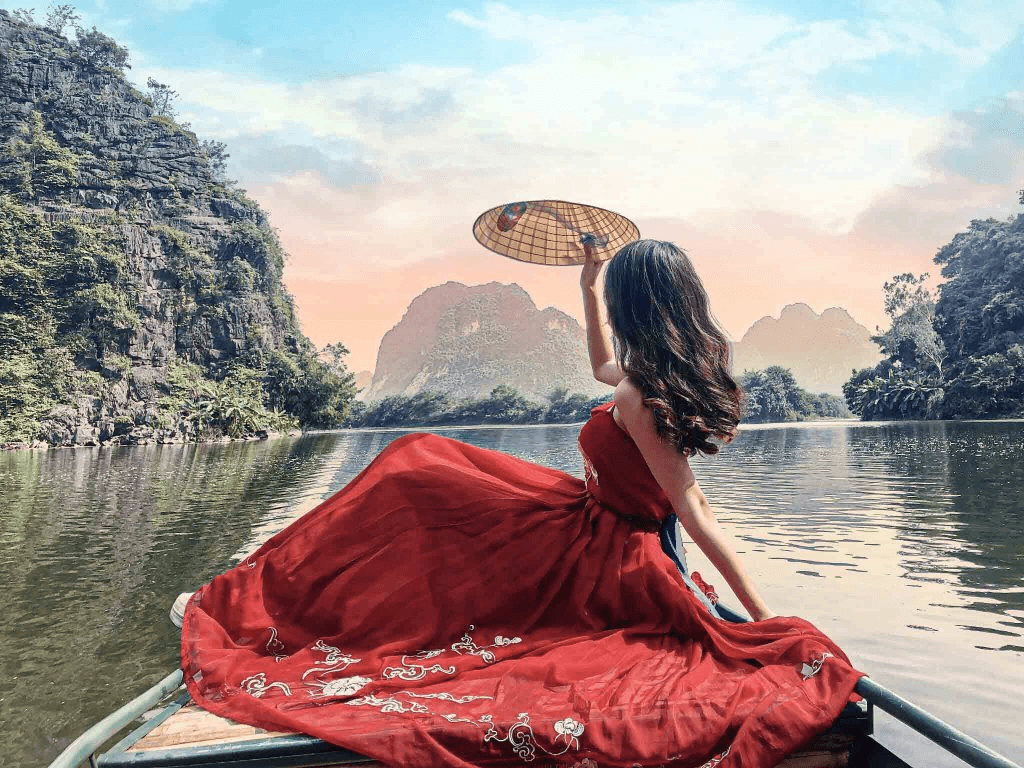 Du khách mặc váy cổ trang đỏ check in trên thuyền nan Tràng An