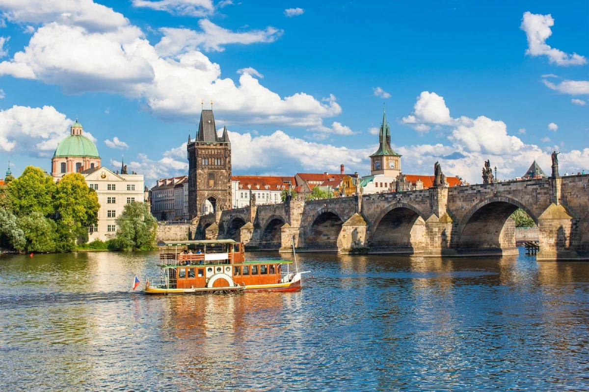 Thuyền du lịch qua cầu Charles cổ kính trên sông Vltava tại Praha